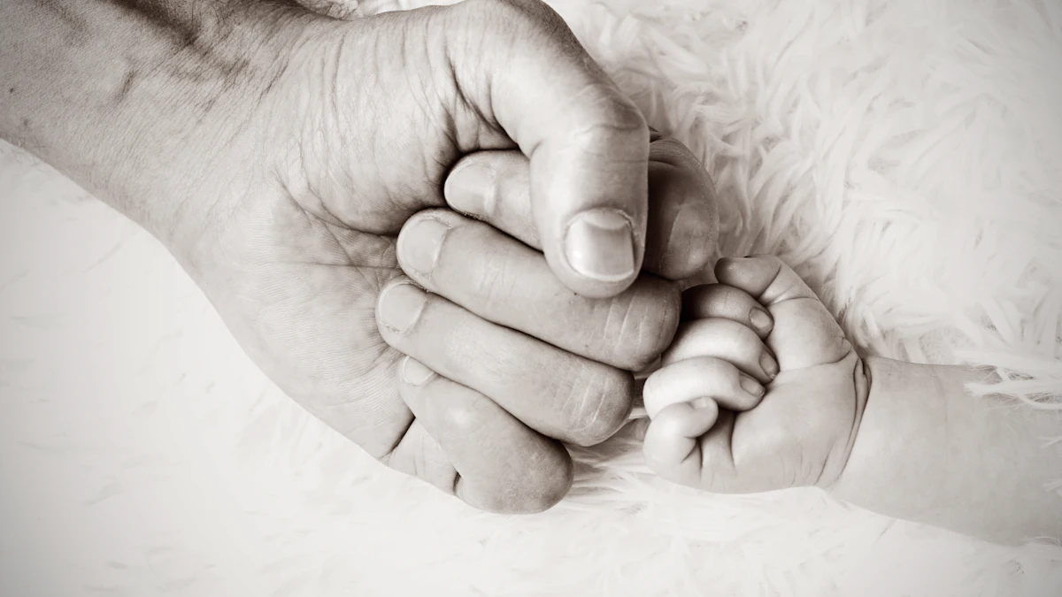 Close-up of an adult's hand holding a newborn baby's small hand