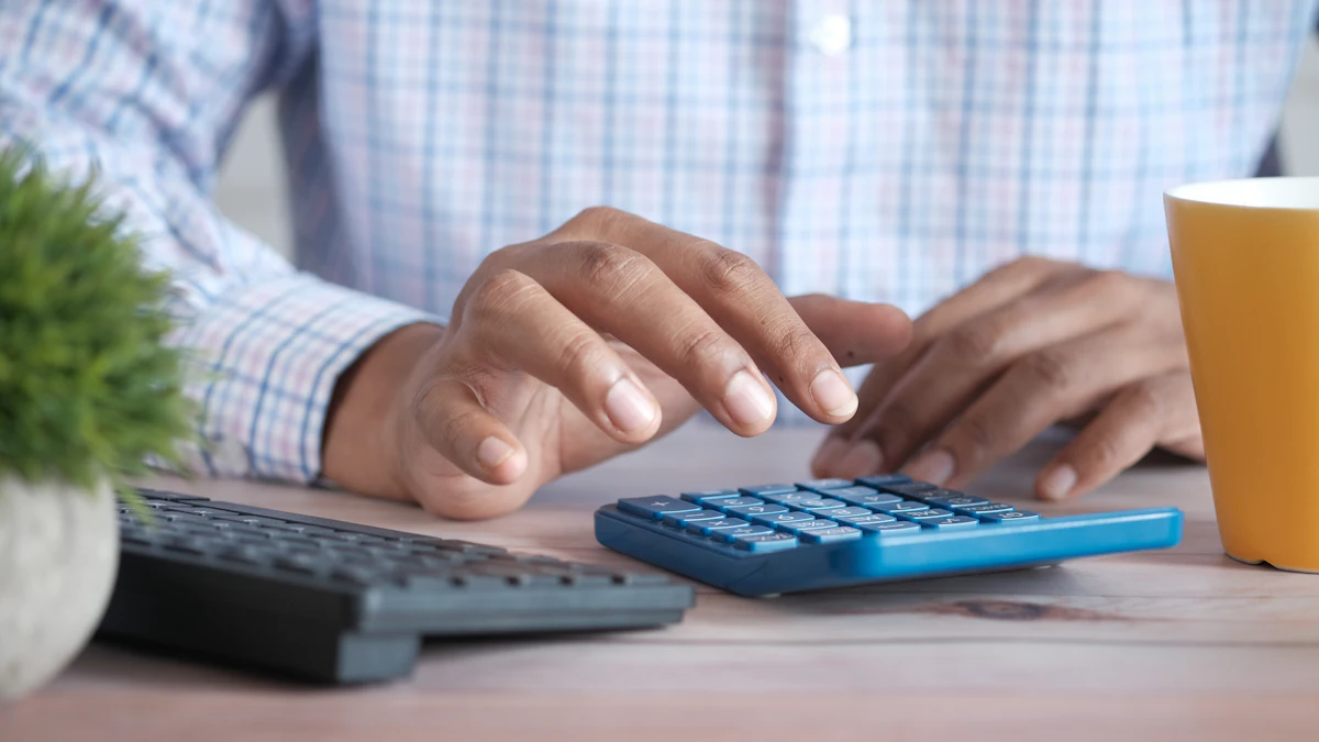 A hand using a calculator on a desk beside a coffee mug