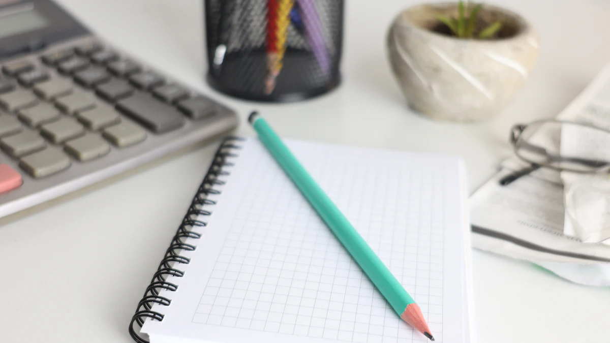 A desk with a calculator, a notebook, a pencil and a small plant